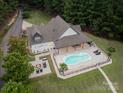 An aerial view showcasing a home's backyard with pool, outdoor seating, a fire pit, and lush landscaping at 1046 Sutton Spring Rd, York, SC 29745