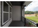 View of wood grain porch with black railings and trim with light gray siding and lawn in background at 433 Nathaniel Way # Brx0033, Charlotte, NC 28213