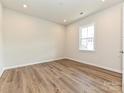 A bright, empty bedroom featuring a window, wood-look flooring, and neutral walls at 8021 Franklin Trail St, Mint Hill, NC 28227