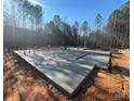 Newly poured concrete foundation with plumbing in place amid a wooded setting ready for new construction at 1025 Baylor Grv, Monroe, NC 28112