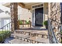 Welcoming front porch with stone steps, a cozy bench with green pillows, and elegant black door at 5916 Bridger Ct, Charlotte, NC 28211