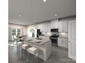 Stylish kitchen featuring white cabinets, granite countertops, a kitchen island with seating, and stainless steel appliances at 203 Alden Ct, Shelby, NC 28152