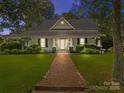Charming home at dusk featuring a brick walkway, manicured lawn, and a welcoming front porch at 405 7Th St, Spencer, NC 28159