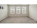 Bright, carpeted bedroom with three large windows, neutral paint, and modern wall-mounted television bracket at 939 Cobbled Way, Fort Mill, SC 29715