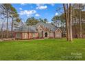 Imposing brick home featuring a well-manicured lawn and lush landscaping, offering timeless elegance and curb appeal at 130 Stonewall Beach Ln, Mooresville, NC 28117