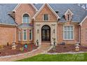 Grand brick home entrance showcasing an arched doorway, stone walkway, and meticulously maintained landscaping at 130 Stonewall Beach Ln, Mooresville, NC 28117