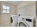 Modern laundry room featuring a large window, washer, dryer, tile floor and wire rack at 16840 Rudence Ct, Charlotte, NC 28278