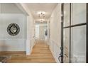 Bright hallway featuring wood floors, white wainscoting, modern lighting, and a decorative mirror at 2621 Ritz Ln, Matthews, NC 28105