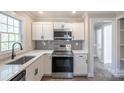 Modern kitchen with white cabinets, stainless steel appliances, and quartz countertops at 83 Woodsdale Se Pl, Concord, NC 28025