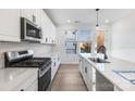 Modern kitchen with white cabinets, stainless steel appliances, gas range, quartz countertops, and hardwood flooring at 1609 Blanche St, Charlotte, NC 28262