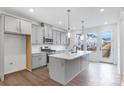 Well-lit kitchen features island with sink, stainless appliances, gray cabinets and modern pendant lighting at 1617 Blanche St, Charlotte, NC 28262