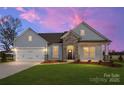 Charming single-story home at sunset featuring stone accents, a two-car garage, and a well-manicured lawn at 3228 Gavin Ln, Harrisburg, NC 28075