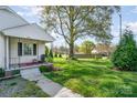 Well-maintained front yard showing an old mature tree and inviting front porch of this single-Gathering home at 630 S Myrtle School Rd, Gastonia, NC 28052
