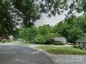 Quaint home featuring a well-manicured lawn, mature trees, and a driveway leading to a cozy residence at 732 Shawnee Dr, Charlotte, NC 28209