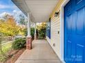 Covered front porch with brick columns and blue door at 16518 Ambassador Park Dr, Huntersville, NC 28078