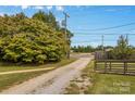 View of a long gravel driveway leading to the property, framed by trees and a wooden fence at 5960/5930 S Main St, Salisbury, NC 28147