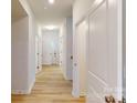 Bright hallway featuring light wood flooring and white doors leading to various rooms at 649 Kitfox Nw Dr, Concord, NC 28027