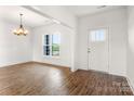 Bright, spacious living room featuring beautiful wood floors, a modern light fixture, large windows, and fresh white paint at 2025 Parks Rd, Salisbury, NC 28147
