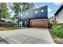 This is a modern home with a black exterior, a stained wood garage door, and a concrete driveway at 2107 W Trade St, Charlotte, NC 28216