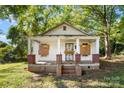 White house with boarded windows, needs renovation. Brick foundation, front porch at 3444 Marvin Rd, Charlotte, NC 28211