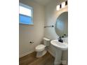 A clean half bathroom showcases a pedestal sink, oval mirror and wood-look tile flooring at 3014 Cunningham Farm Dr, Indian Trail, NC 28079