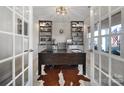 Elegant office with built-in shelving, a large desk, and ample natural light through french doors at 7248 Waterwheel Sw St, Concord, NC 28025