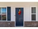 Close-up of a navy front door with a colorful wreath, flanked by windows with brick trim at 1109 Freeman View Dr, Albemarle, NC 28001