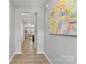 Bright hallway leads to the living area, adorned with a colorful painting and modern flooring at 7059 Duncan Acres Dr, Belmont, NC 28012