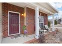 Brick front porch with two wicker chairs and a colorful rooster statue at 7206 Sandown Ct, Harrisburg, NC 28075