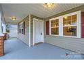 Covered front porch featuring neutral siding, contrasting shutters, and a secure front entry door at 3004 Ridge Ave, Charlotte, NC 28208