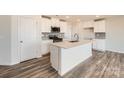 Stylish kitchen features white cabinets, stainless appliances, subway tile backsplash, and large island at 123 Dorian Pl, Troutman, NC 28166