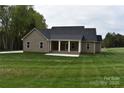 Home exterior with a covered porch, light tan siding, well-maintained lawn, and landscaping at 1117 Shadowmoss Ct, Salisbury, NC 28147