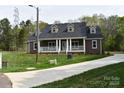 Inviting brick house with a covered front porch, green lawn, and paved driveway at 1117 Shadowmoss Ct, Salisbury, NC 28147