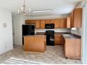 Well-lit kitchen with wooden cabinetry, black appliances, and an island at 1239 Jordans Pond Ln, Charlotte, NC 28214