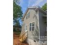 Attractive home showcasing light gray siding, double-hung windows, and a wooden staircase with access to a side door at 1506 7Th St, Statesville, NC 28677