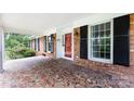 Inviting brick front porch with mosaic tiles, black shutters, and a bright red front door at 5444 Marengo Cir, Charlotte, NC 28216
