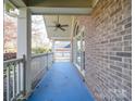 Inviting covered front porch showcasing brick accents, white columns, and a ceiling fan at 909 Woodhurst Dr, Monroe, NC 28110