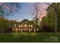 Elegant two-story brick home featuring manicured lawn and mature trees at twilight at 9723 Sedgefield Dr, Waxhaw, NC 28173