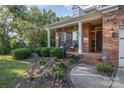 Inviting front porch with classic white columns, seating, and a beautifully landscaped front yard with vibrant flowers at 1001 Hatton Ter, Fort Mill, SC 29707