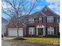 Two-story home with a brick facade, three-car garage, and well-maintained lawn at 13123 Ashley Meadow Dr, Charlotte, NC 28213