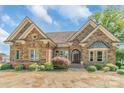 Elegant stone home featuring manicured landscaping, a paved driveway, and inviting entryway at 18212 Pompano Pl, Cornelius, NC 28031