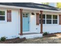 Close-up view of the white brick home featuring updated craftsman-style shutters and a light blue front door at 3503 Linwood Rd, Gastonia, NC 28052