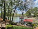 Scenic view of backyard with a covered dock, lush greenery, and lake access at 377 Riverwood Rd, Mooresville, NC 28117