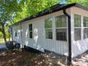Exterior view showcasing the white siding, black trim, and large windows that bring plenty of natural light to the house at 7608 Kershaw Camden Hwy, Kershaw, SC 29067