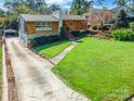 One-story home features a well-manicured lawn, and a concrete driveway with a carport in this tranquil neighborhood at 1166 Montford Dr, Charlotte, NC 28209