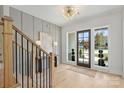Stylish foyer featuring hardwood floors, paneled accent wall, modern light fixture and staircase at 571 Lyttleton Dr, Charlotte, NC 28211