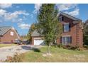 View of the home's exterior showcasing the brick facade, well-maintained lawn, and the driveway leading to the attached garage at 1136 Preakness Nw Ct, Concord, NC 28027