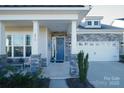 Charming front porch with stone pillars and a bright blue door at 216 Portrait Way, Indian Trail, NC 28079