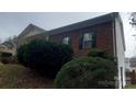 Brick home featuring dark shutters, green bushes, and a sloped lawn at 4000 Wilson Ln, Charlotte, NC 28206