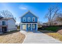 Charming blue two-story home with a welcoming front porch and a concrete driveway at 518 Herms Ave, Mount Holly, NC 28120